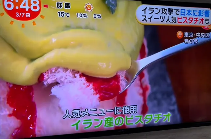テレビ番組でスプーンですくうピスタチオソースのかかったかき氷が紹介されている様子